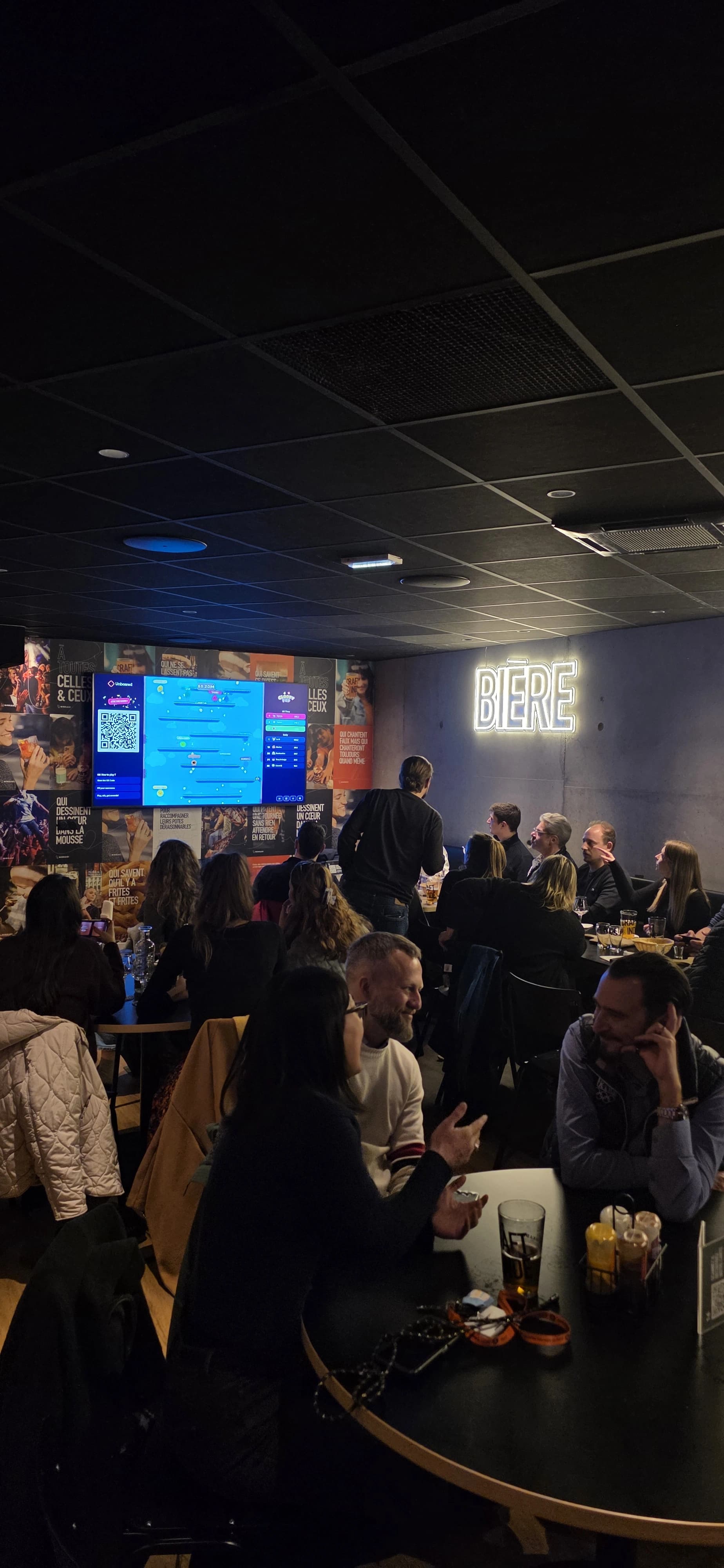 Soirée Unboared dans un bar Ninkasi : la salle est pleine, tous les clients jouent téléphone en main face à la TV